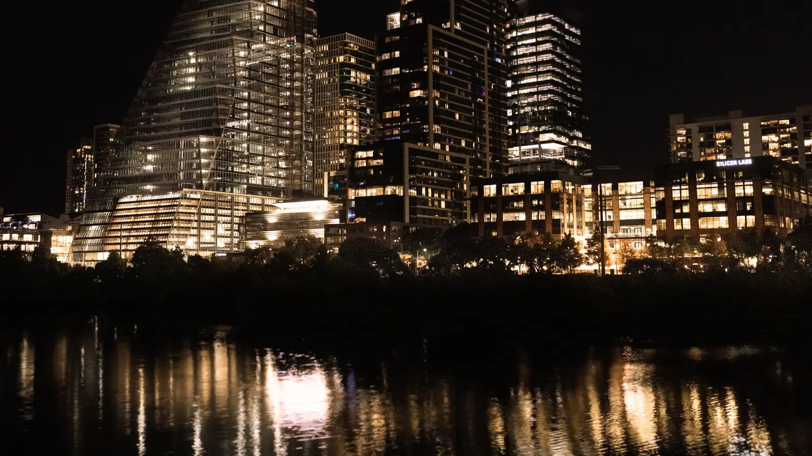 The downtown Austin, Texas skyline lit up at night and reflected in the river